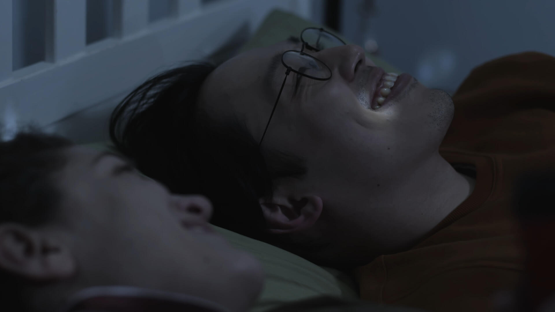 One-Sided Window Still 4 The leading couple lay on a bed, looking up at the ceiling. They laugh; their faces lit by small reflections of light